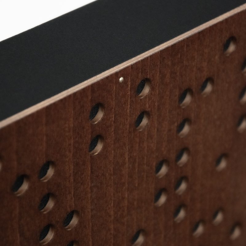 Détail du coin du Diffuseur Binaire - façade Mahogany, perforation et tissu de revêtement noir